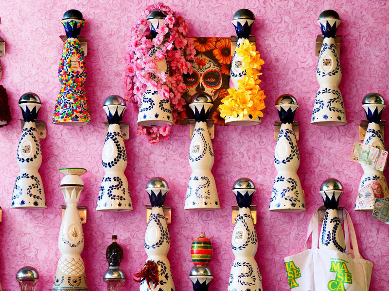 Decorative wall art with colorful figurines and skulls on a pink background