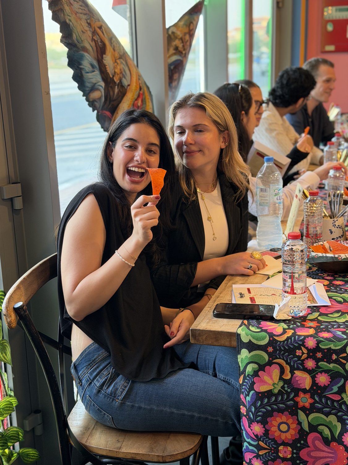 Two guests laughing over a fresh salsa tasting at a Querida masterclass