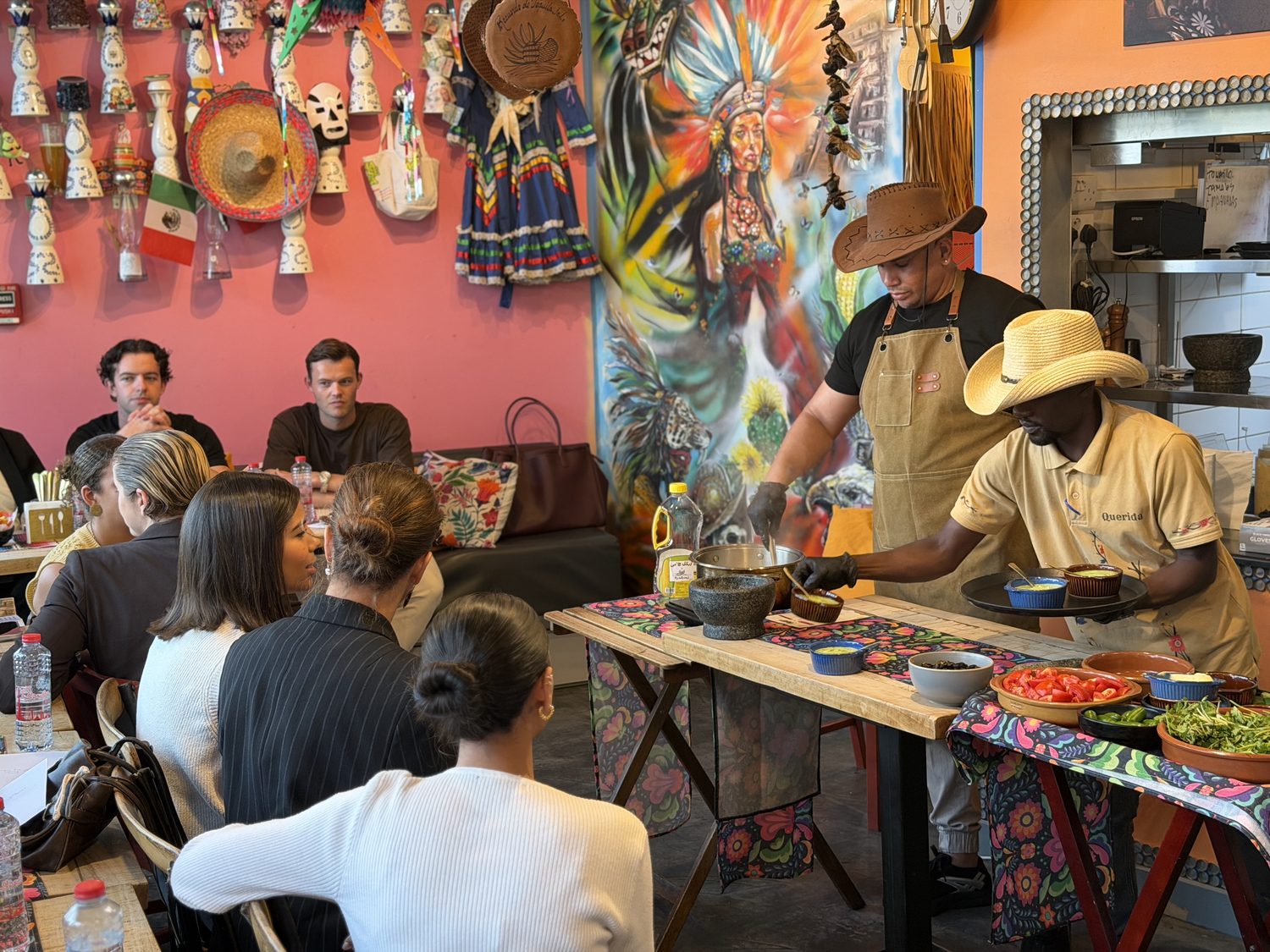 The chef leading the class at a demo table laid with fresh salsa ingredients